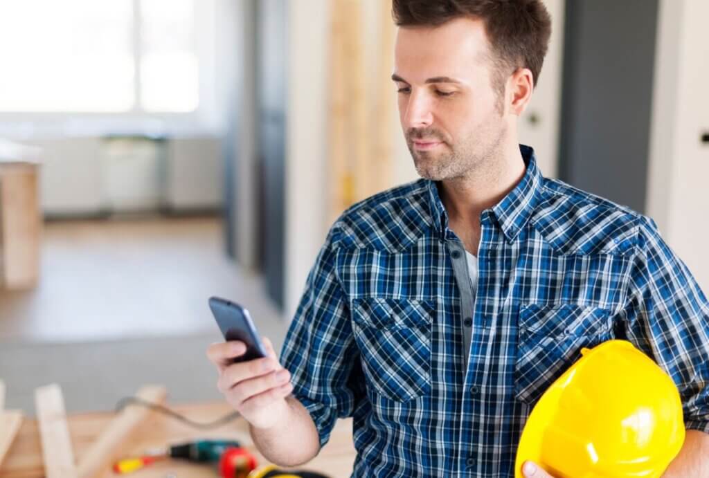 Handwerker mit smartphone und handwerker software auf der baustelle